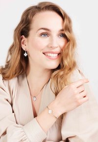 Sieradenset met een bloemdesign in zilver met witte accenten. Bevat dangle oorbellen en een armband met vergelijkbare motieven.