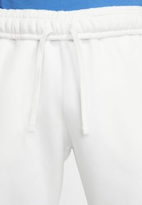 Vita bomullssweatpants med dragsko i midjan, har en slät textur och ett elastiskt midjeband. Inga synliga mönster eller detaljer.