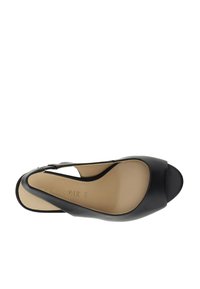 Scarpa slingback nera in pelle con punta aperta, dal texture liscia e design leggermente curvo. Presenta una tracolla regolabile per una vestibilità sicura.