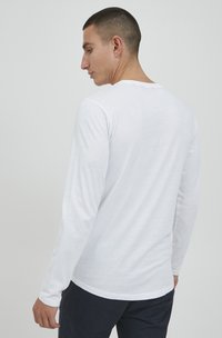 Wit longsleeve T-shirt van zacht materiaal. Heeft een ronde halslijn en een ontspannen pasvorm, met een gladde textuur en een minimalistisch ontwerp.