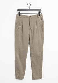 Béžové zúžené kalhoty s knoflíkovým zapínáním, čtyřmi kapsami a hladkou texturou látky, visící na černém ramínku na bílém pozadí.