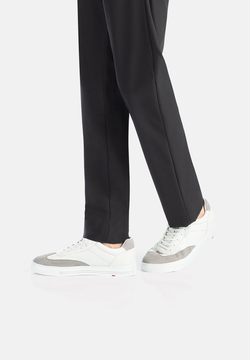 Sneaker bianco e grigio con una combinazione di materiali lisci e scamosciati, design low-top, punta tonda e suola piatta in gomma.