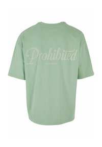 Šviesiai žalia per didelė T-shirt, pasižyminti sklandžia tekstūra, apvaliu kaklu ir žodžiu "Draudžiama" dideliu kursyvu ant nugaros.