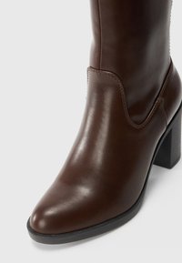 Bruna läderankelstövlar med rund tå och klack i blockstil, med synliga sömmar och en slät yta.