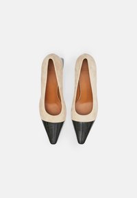 Beiga mockasinklederpumps med spetsig tå och svart texturerad tåhätta. Mjuk insida med lågt snitt. Gummisula för bra grepp.