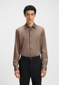 Lange bruin overhemd met een gladde textuur, knoopsluiting aan de voorkant en een klassieke kraag, gecombineerd met zwarte broek.