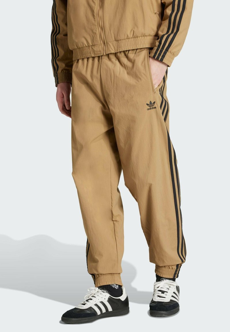 Light brown track jacket and pants made of smooth, lightweight material. Features black three-stripe accents on sleeves and pant sides.