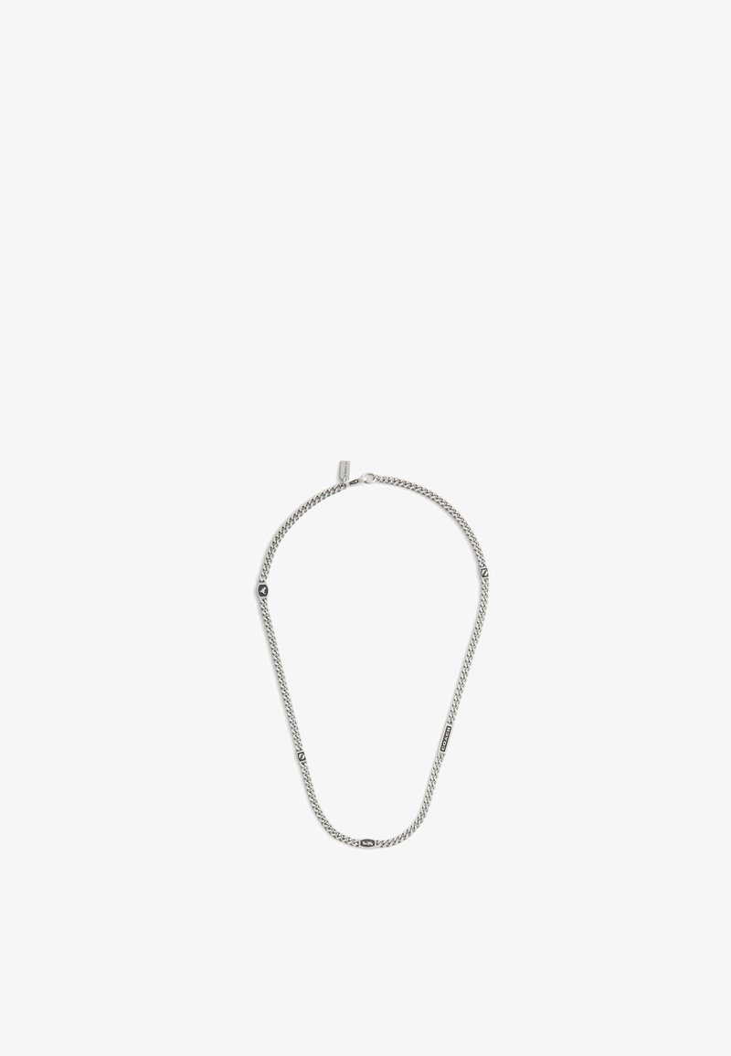 Silverfärgad kedjehalsband med små graverade rektangulära och hexagonala berlocker jämnt fördelade längs kedjan på en vit bakgrund.