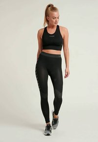 Fekete sportmelltartó és leggings szett, texturált dizájnnal, testhezálló fazonnal és kontrasztos csíkos mintával az oldalon.