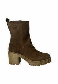 Botín de ante marrón hasta el tobillo con un tacón grueso y estriado y una puntera ligeramente redondeada. Detalle de asa en la parte posterior, acentos de costura mínimos.