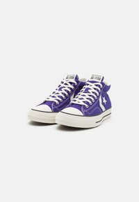 Fialové plátěné vysoké tenisky s bílými gumovými podrážkami, kontrastními bílými tkaničkami a hvězdovým logem na straně. Klasický design s akcenty prošívání.