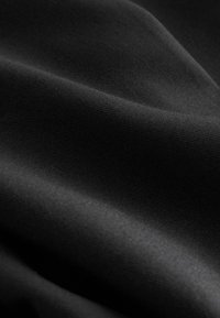 Tissu noir lisse avec des plis subtils et une texture douce sous un éclairage doux.