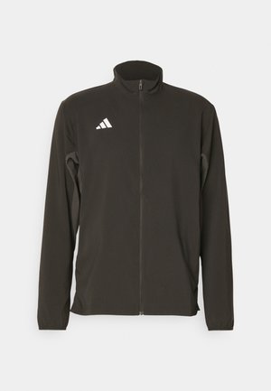 Must läätspakist must zip-up jakk on valmistatud kerge kangast. Omab kõrget kraed ja kolme valget diagonaaltriipu vasakul rinnaosas.