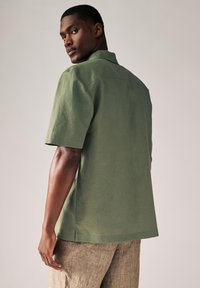 Kortærmet, olivengr�øn skjorte i letvægtsstof. Har klassisk krave og afslappet pasform med lige kant og sidelommer.