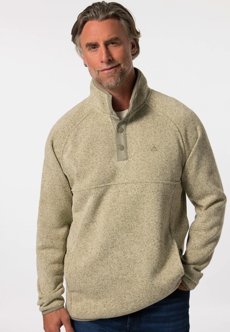 Lys beige fleece-pullover med høj krave, trykknapper og en tekstureret overflade. Har et subtilt mønster og en afslappet pasform.