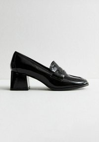 Black patent leather block heel pump with a rounded toe and a decorative band across the vamp. Smooth texture with a shiny finish.