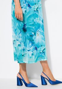 Blommig midiklänning i blå och turkos tyg med livligt blommönster; matchad med blå satin slingbackklackar med en kraftig klack.