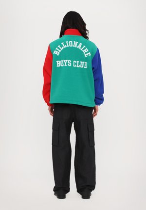 Fleecejakke med røde, grønne og blå paneler samt "Billionaire Boys Club" tekst på ryggen; parret med sorte cargo bukser.