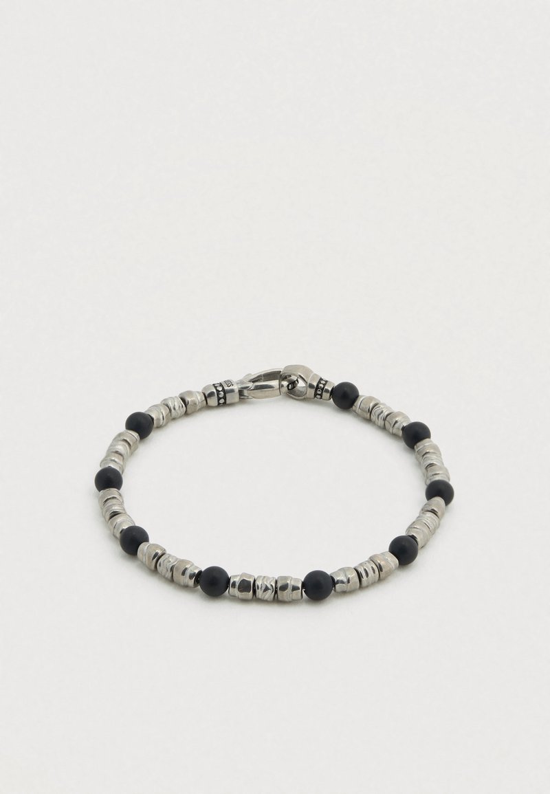 Bracelet en perles noires et argentées présentant des formes rondes et tubulaires alternées, un éclat métallique et une fermeture à clip.