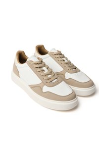 Beige und weiße Sneakers mit einem strukturierten Obermaterial, glatten Akzenten, Schnürdesign und einer dicken weißen Sohle.