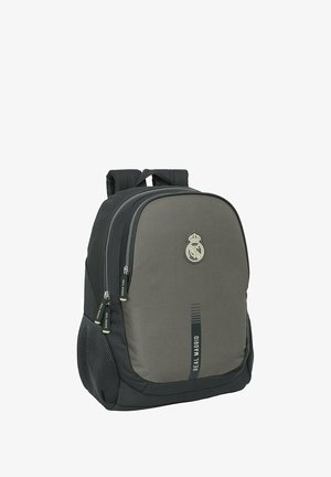 Sac à dos en tissu gris avec un design lisse et arrondi, logo du Real Madrid, deux zippers à l'avant et des accents en maille sur les côtés.