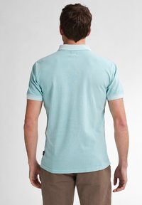 Polo shirt azzurro chiaro con maniche corte, realizzato in un tessuto morbido, con colletto classico e dettagli di cucitura visibili.