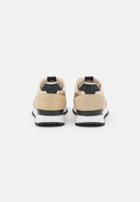 Sneakers con una combinazione di colori nero e oro, tomaia in suede e mesh, forma arrotondata, colletto imbottito e suola bianca a contrasto.