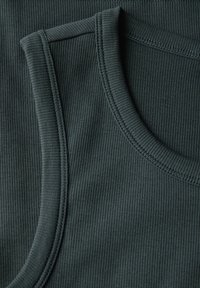 Débardeur côtelé vert foncé avec un col rond. Le tissu présente une légère texture, avec des côtes horizontales et des coutures renforcées.