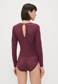 Burgundivörös, hosszú ujjú body, texturált mintával, kulcslyuk hátkivágással és szoros fazonnal. Puha, rugalmas anyag, sima felülettel.