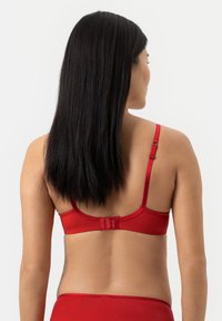 Rode beha met een gladde satijnen afwerking, voorzien van verstelbare bandjes en een haak-en-oogsluiting aan de achterkant. Eenvoudig ontwerp, minimale details.