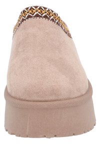 Suedekänga i ljusbeige med texturerad yta, med en flätad detalj i brunt och guld vid kragen och en vadderad sula.