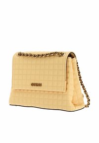 Borsa trapuntata gialla con tracolla in oro, chiusura magnetica e il logo in evidenza sulla parte anteriore.