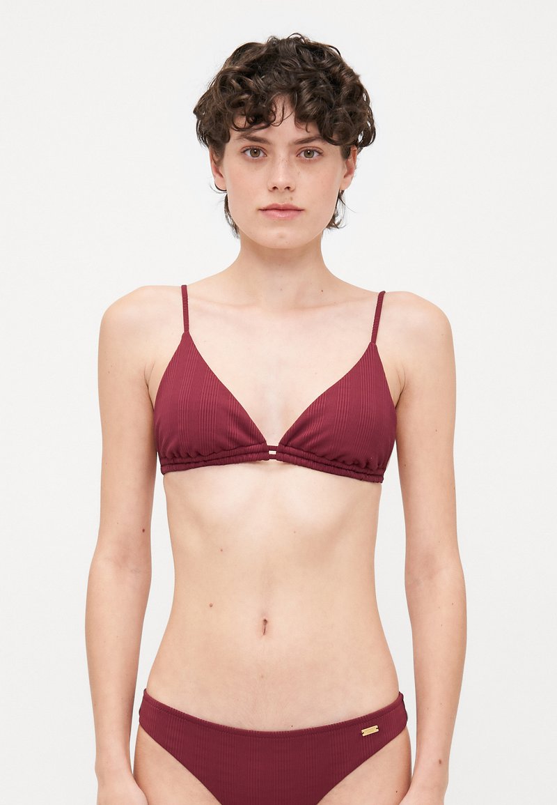 Burgundy ribbed bikini with triangular top, thin adjustable straps, and gathered detailing; matching bottoms with minimal side coverage.