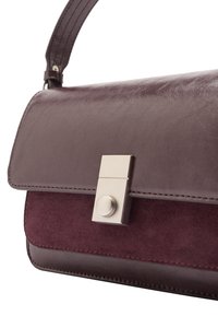 Ciemnofioletowa skórzana torebka o gładkim wykończeniu z zamszowymi akcentami, wyposażona w metalowe zapięcie i usztywniony, prostokątny kształt.
