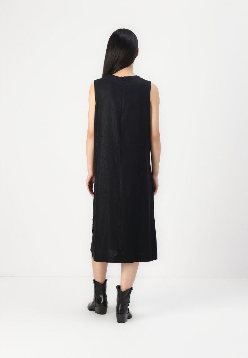 Schwarzes ärmelloses Kleid mit gerader Silhouette, knielang, aus leichtem Stoff. Verfügt über einen Reißverschluss auf der Rückseite und seitliche Schlitze für Bewegungsfreiheit.