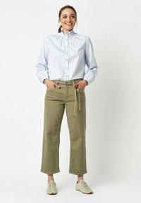 Light blue striped button-up shirt with ruffled collar, paired with olive green wide-leg pants and beige sneakers. Simple and casual design.