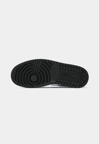 Čierna podrážka tenisky Nike s okrúhlymi a mriežkovými vzormi a logom Nike v strede na bielom pozadí.