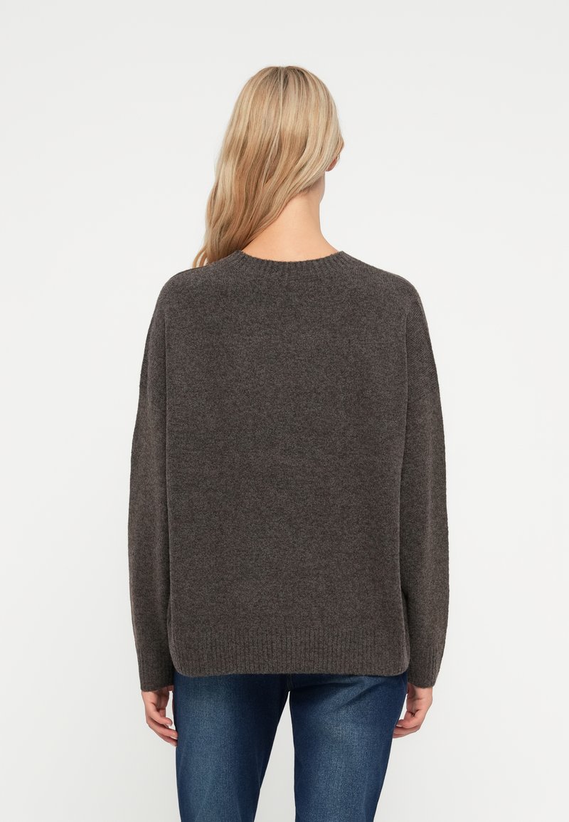 Pull en tricot gris foncé avec une coupe décontractée, col rond et manches longues. Présente un ourlet côtelé et des fentes sur les côtés, confectionné dans un matériau doux et texturé.