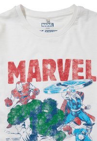 Camiseta blanca de algodón que presenta una colorida impresión gráfica de superhéroes de Marvel con la palabra "MARVEL" en letras rojas en negrita arriba.