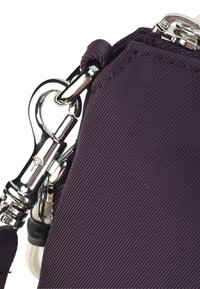 Borsa a tracolla in tessuto viola con chiusura e dettagli in metallo argentato, caratterizzata da una texture a righe e accenti a contrasto.