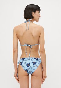 Tvådelad bikini i ljusblått tyg med blommönster. Halterneck med band och justerbara sidosträngar på botten. Slen textur.