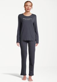 Mörkgrå pyjamasset med långa ärmar som har rund halsringning och varumärkeslogo på toppen. Mjukt tyg med raka byxben.