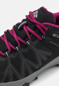Czarny but trekkingowy z różowymi sznurowadłami, wykonany z siateczkowego materiału, z gumową podeszwą. Posiada teksturowane nakładki oraz wzmocniony czubek dla dodatkowego wsparcia.