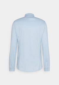 Camicia azzurro chiaro a maniche lunghe in tessuto liscio, con colletto e polsini abbottonati, orlo curvo e senza motivi visibili.