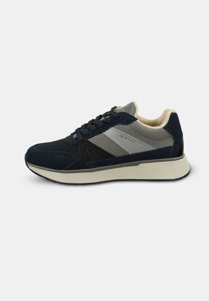 Navy and gray GANT sneaker with mesh and suede panels, cushioned beige interior, black laces, and beige sole on white background.