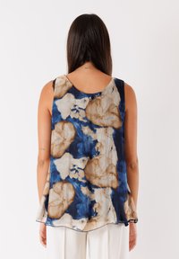 Canotta senza maniche in blu, beige e crema con motivo floreale; tessuto leggero e fluido con scollo rotondo e un delicato dettaglio sull'orlo.