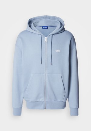 Lys blå hettejakke med glidelås laget av mykt stoff, med kengurulomme, justerbar snorhette og en liten hvit logo på brystet.