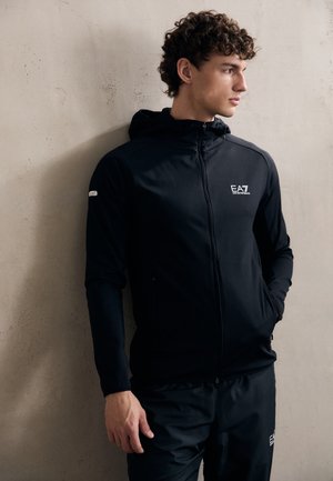 Black zip-up hoodie with a sleek design, featuring a hood, side pockets, and a subtle logo on the chest. Smooth fabric texture.
