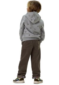 Grauer Hoodie mit Smiley-Druck, braune Cordhosen und Sneakers. Verfügt über eine Kängurutasche und strukturiertes Material. Rückansicht.