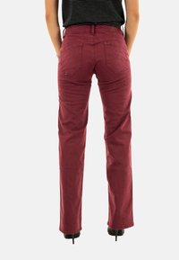 Pantalones burdeos con un diseño de pierna recta, hechos de una tela suave. Presentan dos bolsillos traseros, costuras visibles y una cintura a media altura.